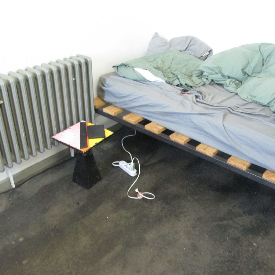 A sad bed with green sheets and DIY nightstand